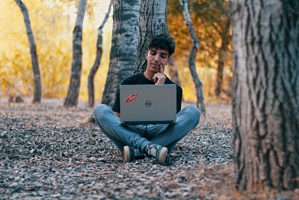 Thoughtful Young Man in Nature Using Screen Time Wisely