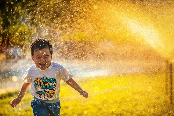 Happy Boy Running Through Sprinkler